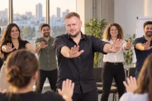 מנחה עומד בחזית ומוביל תרגול ידיים לקבוצת עובדים מחייכים